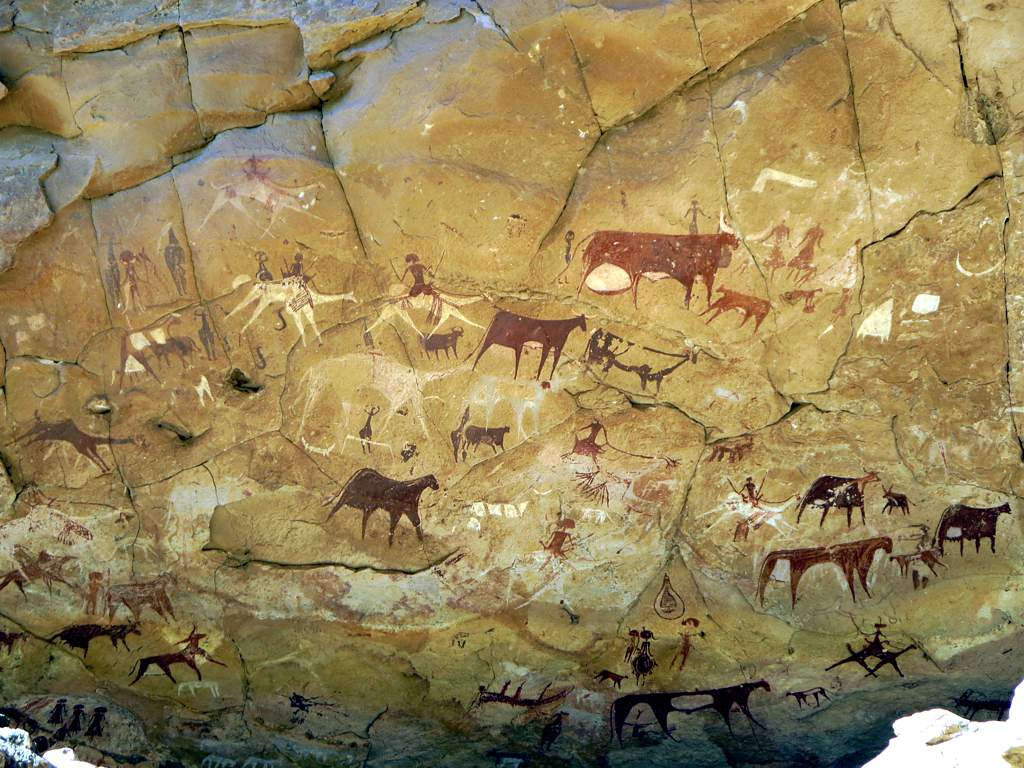 Te prazgodovinske skalne slike so v jami Manda Guéli v gorah Ennedi v Čadu v osrednji Afriki. Kamele so bile naslikane na prejšnje podobe goveda, kar morda odraža podnebne spremembe.