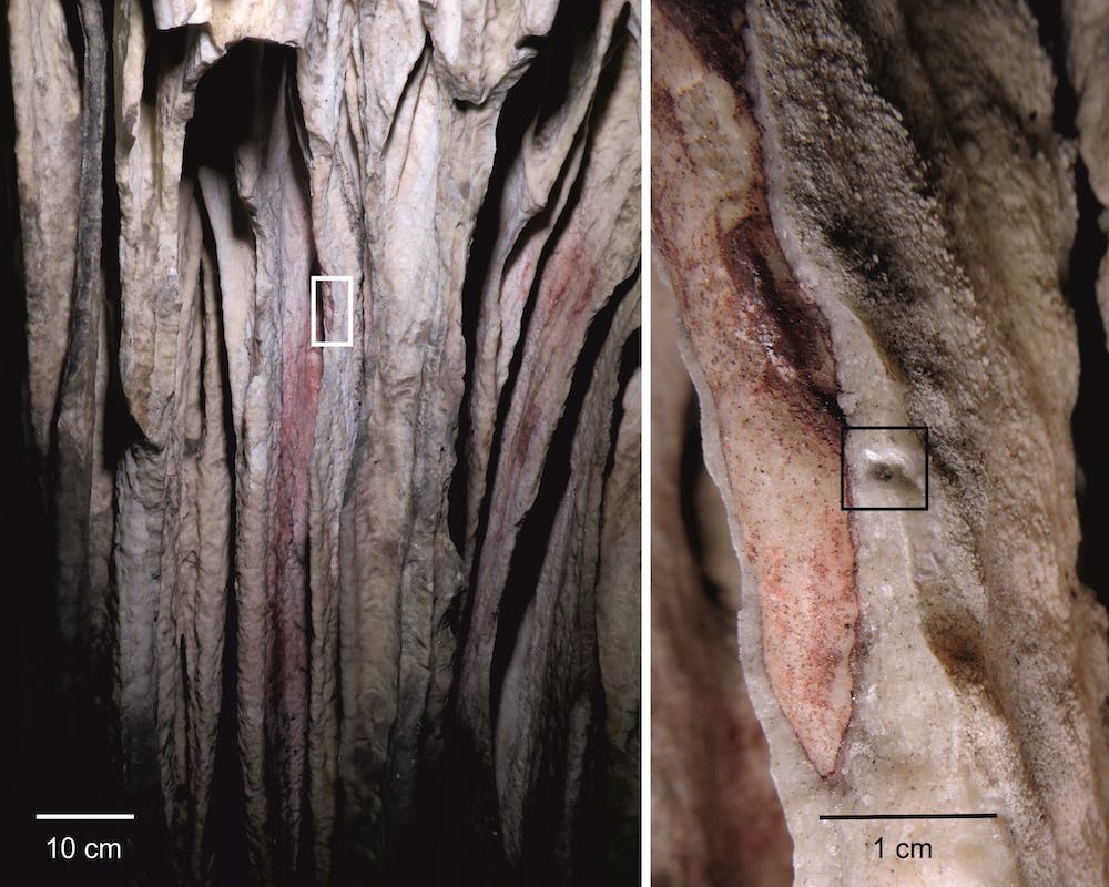 Rött pigment tvättas in i konkaviteterna i ett ljust droppstensdraperi i Ardales Cave.