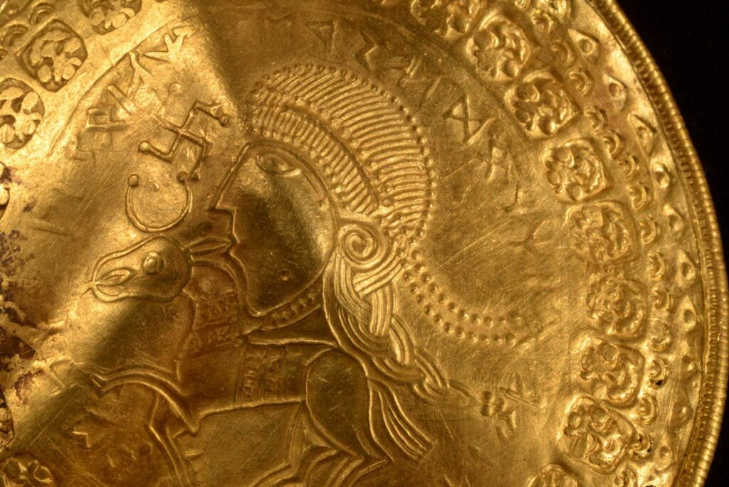 De inscriptie 'He is Odin's man' is te zien in een ronde halve cirkel boven het hoofd van een figuur op een gouden schutblad dat eind 2020 is opgegraven in Vindelev, Denemarken. Wetenschappers hebben de oudst bekende verwijzing naar de Noorse god Odin op een gouden schijf opgegraven in West-Denemarken.